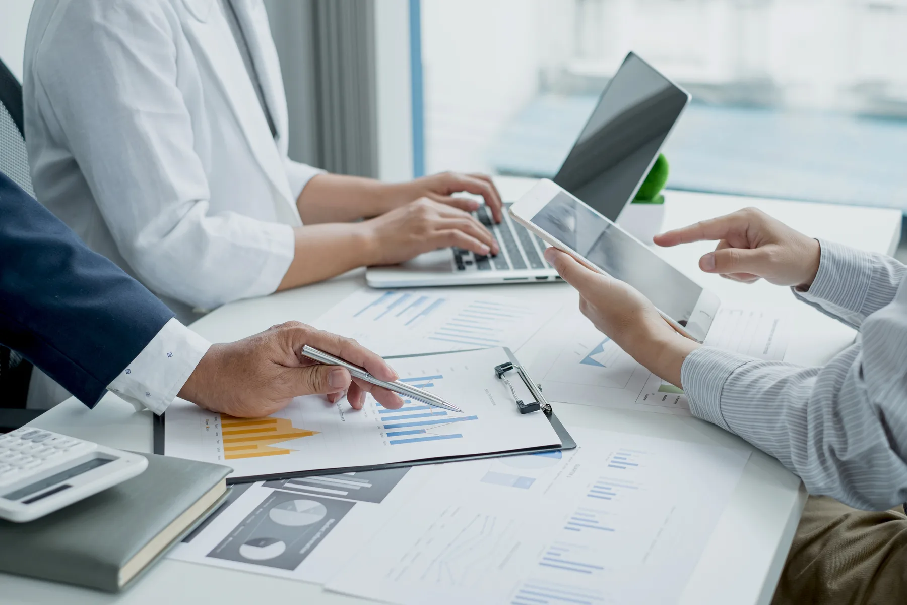 Two business professionals reviewing printed budget charts and graphs together at an office table