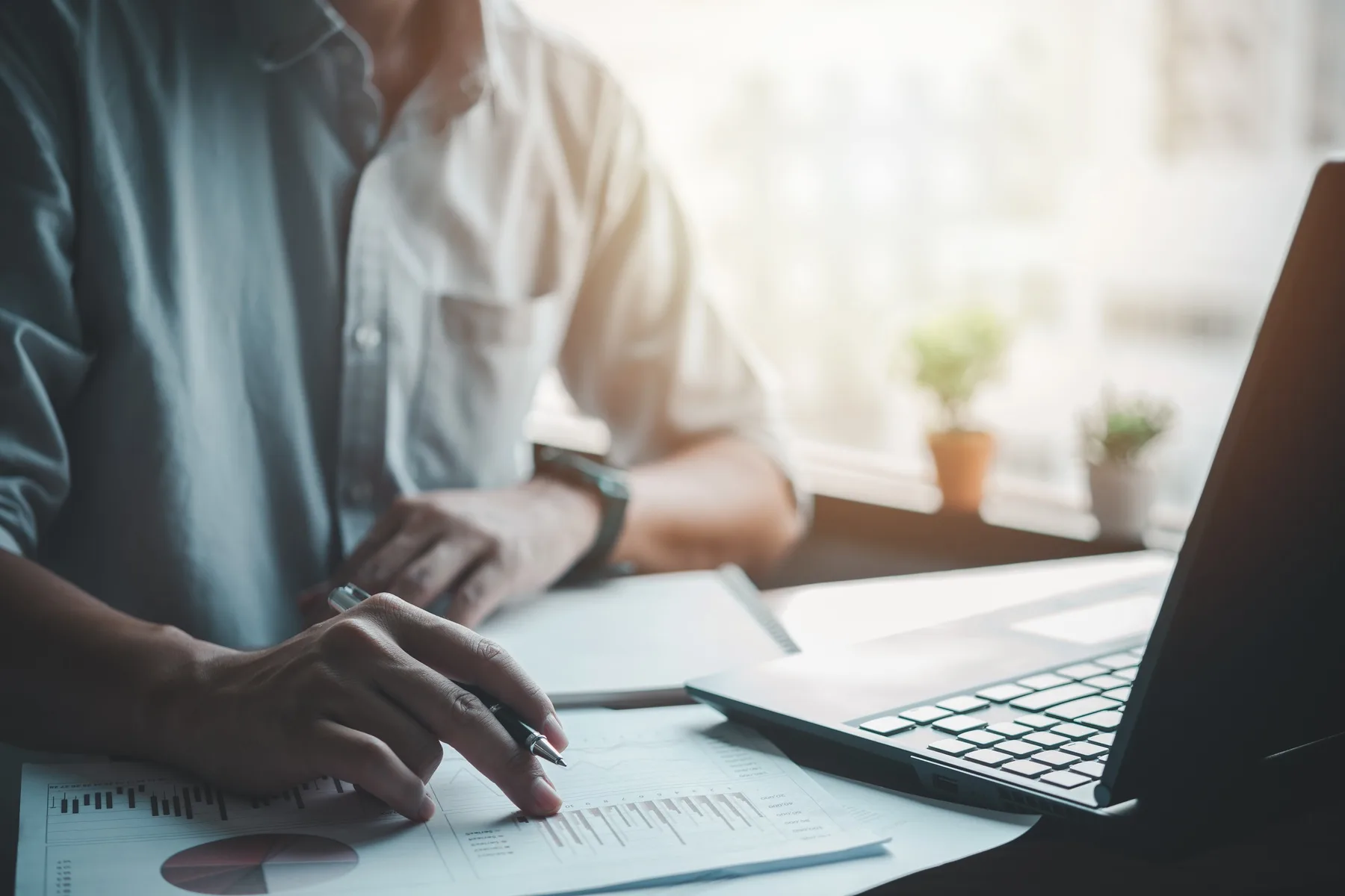 A business owner reviewing marketing performance documents and a laptop at a desk in an office
