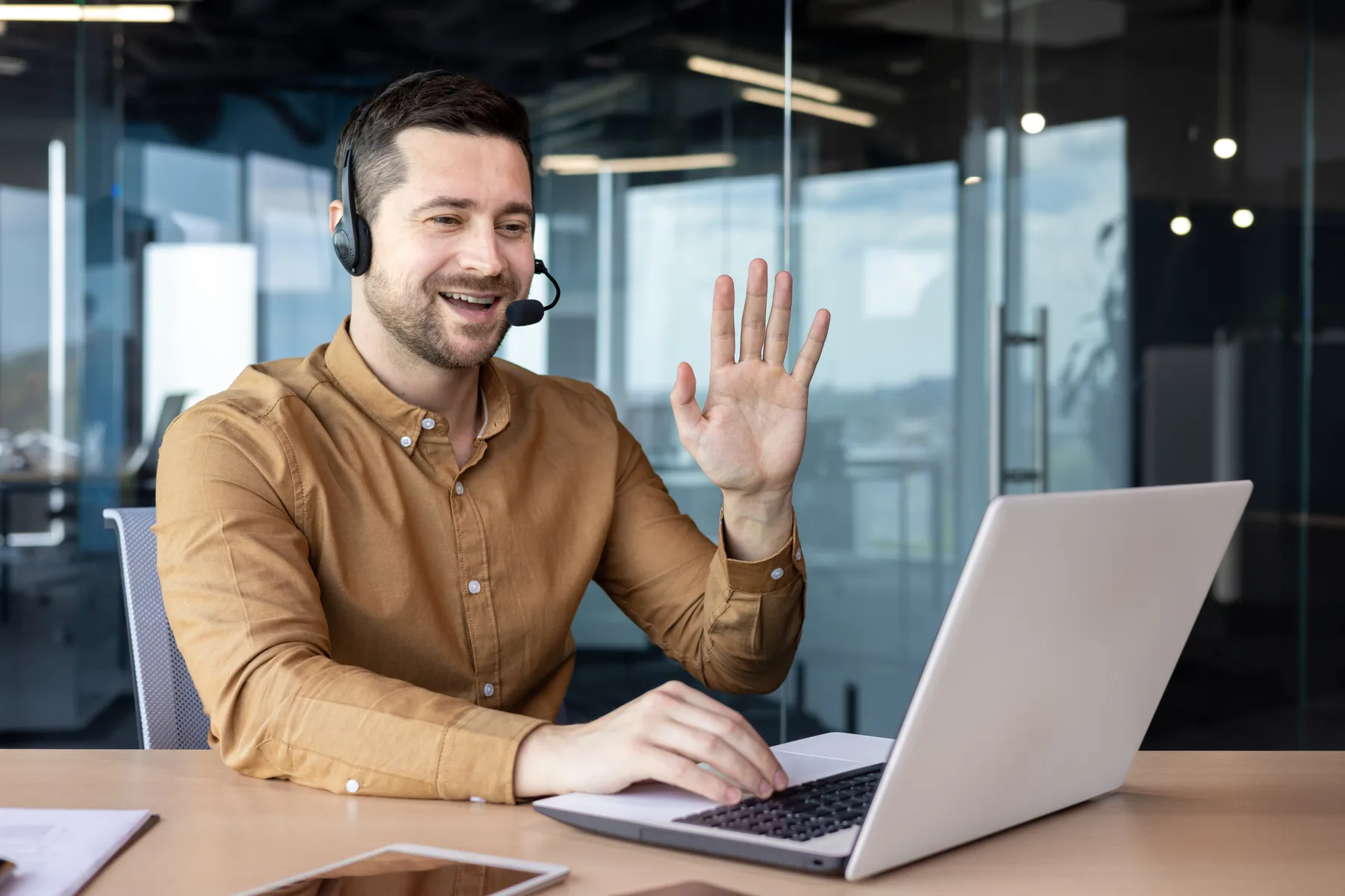 A person having a friendly video call at a laptop in a bright office, representing a real-time video customer support conversation