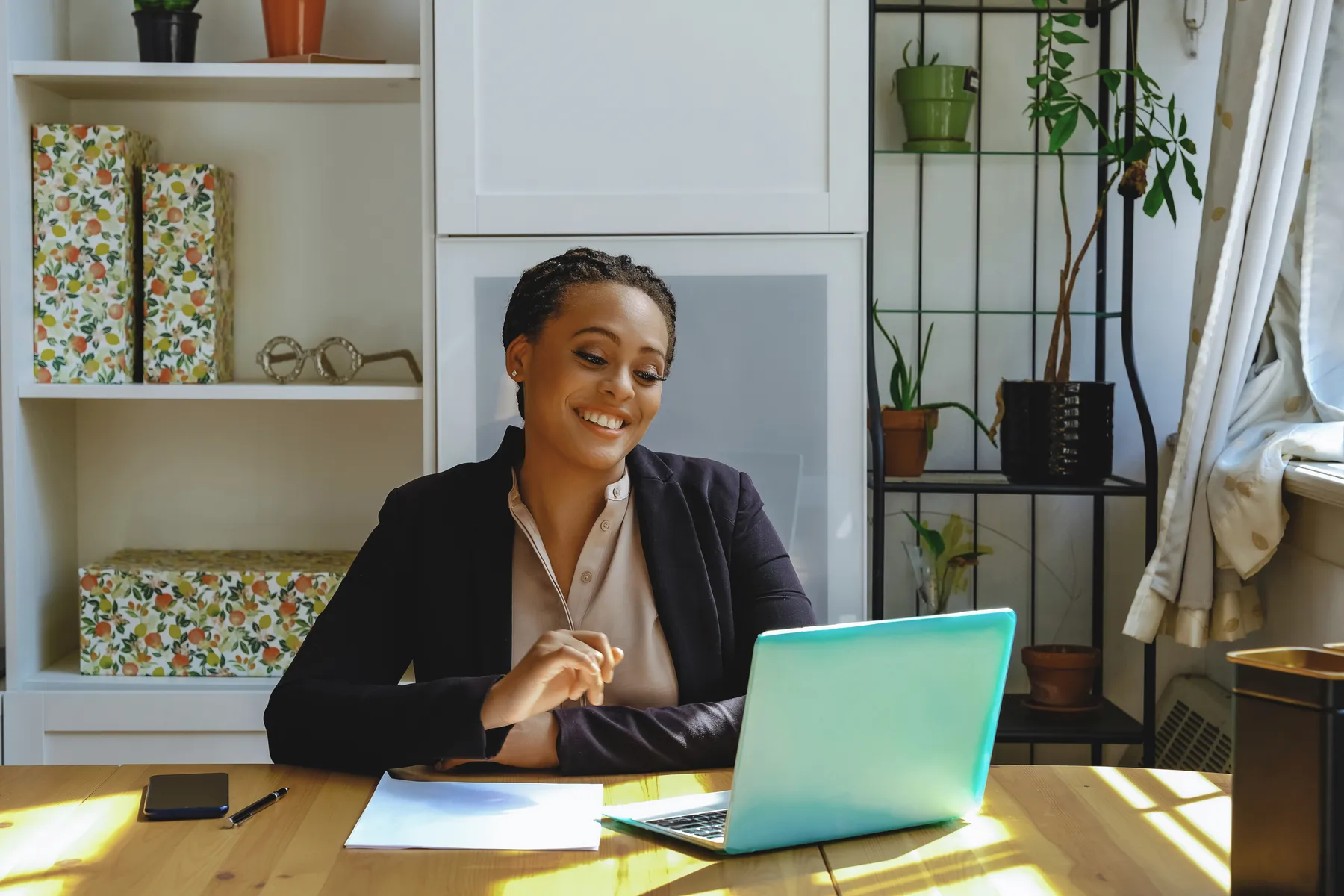 A small business owner smiling while working at a laptop in a bright home office