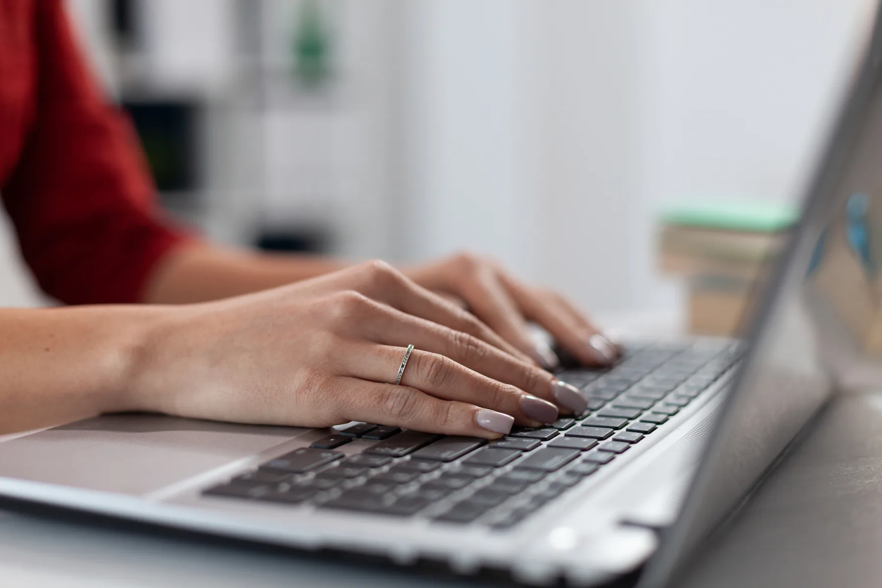 Close-up of a small business owner's hands typing on a laptop keyboard in a bright office