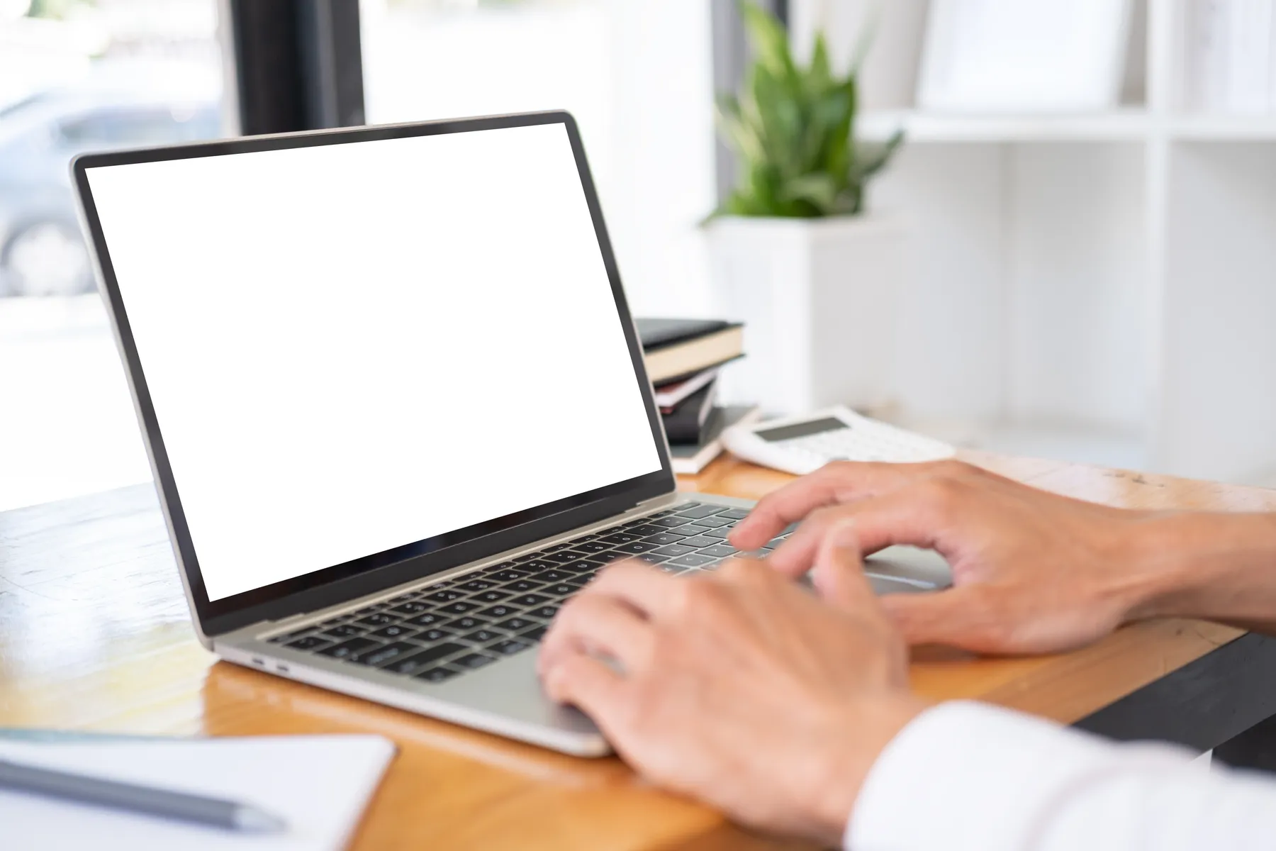 Close-up of a business owner's hands typing on a laptop at an office desk