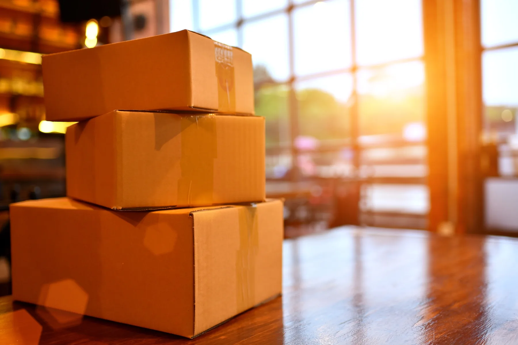 A small retail business owner packing a cardboard shipping box at a workspace surrounded by online-order packaging supplies