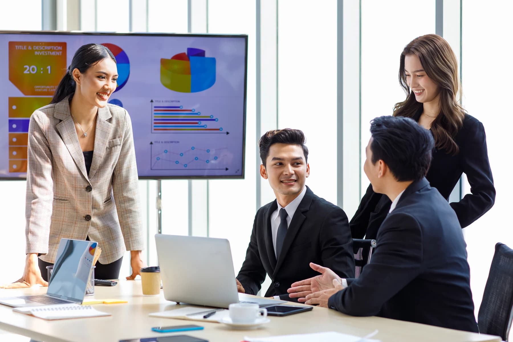 A business team reviewing sales and customer data on a presentation screen in a meeting room