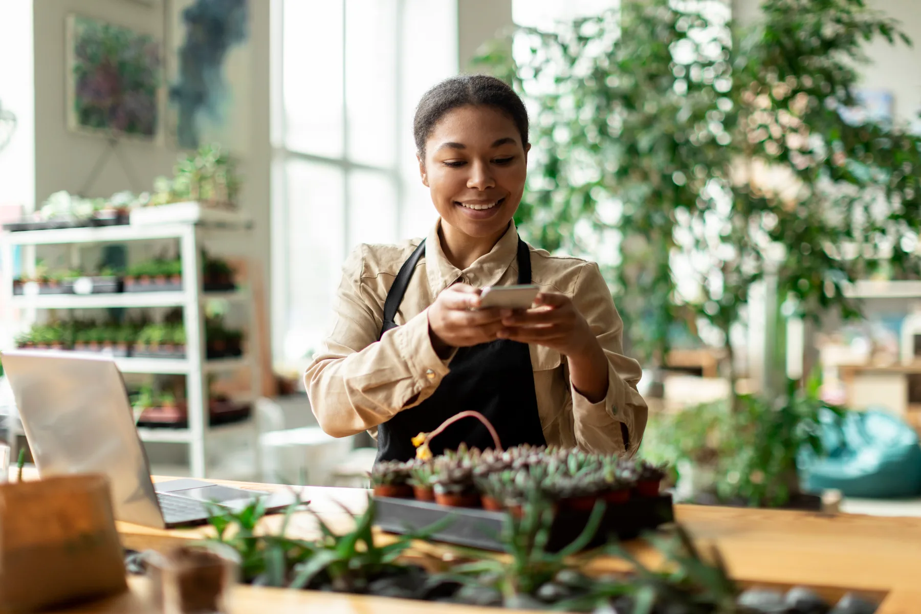 A small business owner photographing her plant shop's products with a smartphone for social media